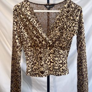 A brown and gold patterned velvet long-sleeve top with a ruched v-neckline, hanging on a white hanger against a white background.
